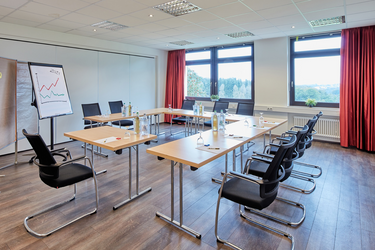 Tagungsraum im Hotel FIT mit Tischen und Stühlen für Meetings und Veranstaltungen.