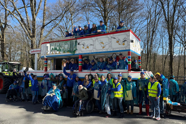 Gruppe verkleideter Menschen vor einem Karnevalswagen.