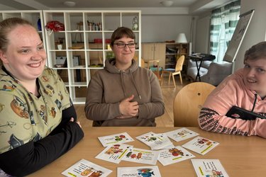 Drei Frauen sitzen am Tisch und unterhalten sich
