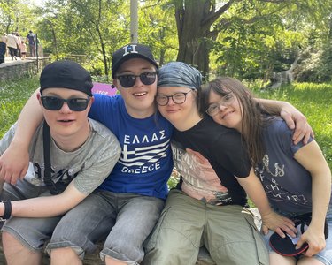 ehrere Bewohner sitzen draußen nebeneinander und legen die Arme umeinander.