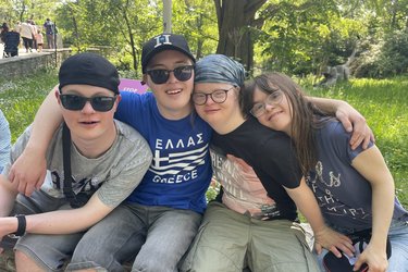 ehrere Bewohner sitzen draußen nebeneinander und legen die Arme umeinander.