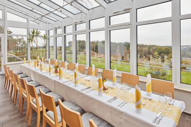 Wintergarten im Hotel FIT mit langer Essenstafel.