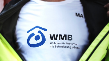 Foto einer Person, die ihre Jacke öffnet und ein T-Shirt mit WBM-Logo trägt.